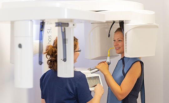 Assistentin diskutiert mit einer Patientin am 3D-Scanner