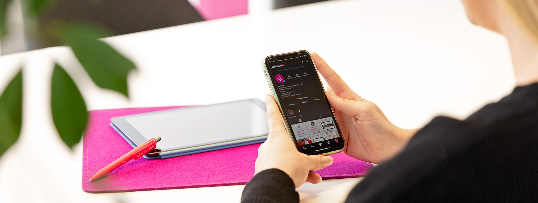 Frau schaut auf einem Handy das Instagram Konto von praxiskom an